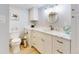 Bright bathroom featuring white cabinets, marble countertops, and a decorative round mirror at 3700 S Atlantic Ave # 111, New Smyrna Beach, FL 32169