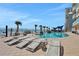 Community swimming pool with lounge chairs, palm trees, and ocean views at 3703 S Atlantic Ave # 507, Daytona Beach Shores, FL 32118