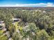 Expansive aerial view of the home and acreage surrounded by lush trees against a blue sky at 4252 Quail Ranch Rd, New Smyrna Beach, FL 32168