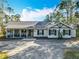 Charming single-story home featuring a covered porch, black shutters, neutral stucco, and mature trees at 4252 Quail Ranch Rd, New Smyrna Beach, FL 32168