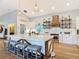 A modern kitchen features an island with seating, a wooden range hood, and open shelving with stylish decor at 4252 Quail Ranch Rd, New Smyrna Beach, FL 32168
