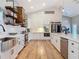Modern kitchen featuring white cabinets, stainless steel appliances, a decorative wooden range hood, and open shelving at 4252 Quail Ranch Rd, New Smyrna Beach, FL 32168