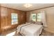 Bright bedroom offers a cozy feel, with wood paneling accents and two large windows with curtains at 55634 Sam St, Astor, FL 32102