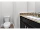 Stylish half bath with granite countertop, dark wood vanity and tiled floor at 559 Coronado Cove Rd, New Smyrna Beach, FL 32168