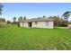 Expansive backyard featuring lush green grass and a sliding glass door entrance to the home at 599 S Cedar Ave, Orange City, FL 32763