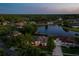 Panoramic aerial view of a lakeside neighborhood at twilight, showcasing homes with screened pools and lush greenery at 6071 Sabal Hammock Cir, Port Orange, FL 32128