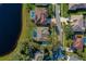 Aerial view of the property featuring a screened pool, lush green lawn, and proximity to a serene lake at 6071 Sabal Hammock Cir, Port Orange, FL 32128
