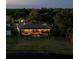 Aerial view of a backyard with a screened pool, lounge chairs, dining area, and well-maintained green space at twilight at 6071 Sabal Hammock Cir, Port Orange, FL 32128
