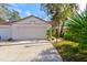 View of the home's garage and a paved driveway with landscaping and a lamp post at 6152 Sequoia Dr, Port Orange, FL 32127
