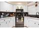 Well-lit kitchen featuring white cabinets, black appliances, and neutral tile flooring at 6157 Sequoia Dr, Port Orange, FL 32127