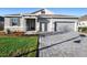 Charming single-story home featuring a stone facade, gray exterior, paver driveway, and well-manicured lawn at 875 Honey Petal Ln, Deland, FL 32720