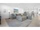 Open-concept living room with gray sectional sofa, neutral carpet, and views of the kitchen at 875 Honey Petal Ln, Deland, FL 32720