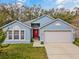 Charming single-story blue home with a red front door and attached two-car garage at 971 Cascades Park Trl, Deland, FL 32720