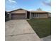 Ranch-style house exterior featuring brick facade, well-manicured lawn, and attached garage at 1420 Felton St, Deltona, FL 32725