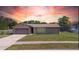 Charming single-story home with an attached garage, well-kept lawn and colorful sunset backdrop at 1420 Felton St, Deltona, FL 32725