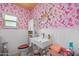 Quirky bathroom with pink mermaid wallpaper, white vanity, and unique circular mirror at 1489 Casey Ln, Port Orange, FL 32129