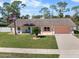 Charming single-story home with a manicured lawn, palm tree, sidewalk and two-car garage at 1489 Casey Ln, Port Orange, FL 32129