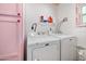 Functional laundry room with modern washer and dryer units, pink cabinet and shelving at 1489 Casey Ln, Port Orange, FL 32129