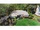 Aerial view of a brick home with manicured lawn, mature trees and shrubs and pristine landscaping at 1552 Covered Bridge Dr, Deland, FL 32724