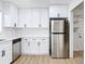Modern kitchen with stainless refrigerator and dishwasher plus bright white cabinets at 1579 Brady Dr, Deltona, FL 32725