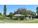 Well-maintained front yard with mature trees, tropical plants, and a charming green home with decorative shutters at 1590 N Page Dr, Deltona, FL 32725