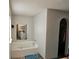 Bright bathroom features a soaking tub, tile surround, and an arched doorway leading to a closet at 2235 Rabenton Rd, Deltona, FL 32738