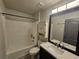 Bathroom featuring vanity sink, mirror, toilet, white tub, white tile, and dark hardware at 2235 Rabenton Rd, Deltona, FL 32738