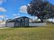 Two-story gray home with a large tree in the front yard, an arched entryway, an attached garage, and a white fence at 2235 Rabenton Rd, Deltona, FL 32738