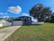 Two-story gray home featuring an arched entryway, attached garage, and a spacious green lawn under a bright blue sky at 2235 Rabenton Rd, Deltona, FL 32738