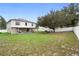 Large, grassy backyard with a two-story home, covered patio, and white fence offering plenty of space for recreation at 3318 Dewberry Dr, Deltona, FL 32738