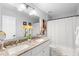 Bathroom with double sinks, granite countertop, modern lighting, and a bathtub with a shower featuring a white curtain at 3318 Dewberry Dr, Deltona, FL 32738