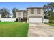 Two-story home featuring an attached two-car garage, a well-manicured lawn, and a neatly landscaped garden bed near the front entrance at 3318 Dewberry Dr, Deltona, FL 32738