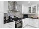 Modern kitchen featuring white cabinets, stainless steel appliances, and a striking backsplash design at 3318 Dewberry Dr, Deltona, FL 32738