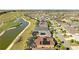 Aerial view showcases home with solar panels, pond, and golf course within a vibrant community at 3432 Wise Way, The Villages, FL 32163