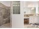 Modern bathroom showcasing stone shower, glass block window, double sink vanity, and decorative lighting at 3432 Wise Way, The Villages, FL 32163