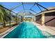 A beautiful screened-in pool with lush landscaping and clear blue water, with a view of the pond at 3432 Wise Way, The Villages, FL 32163