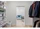 Bright walk-in closet with shelving, a laundry basket, and a view of an adjacent room with a blue sofa at 3432 Wise Way, The Villages, FL 32163