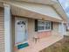 Inviting front porch with tan siding and a white front door with window and 'hello' doormat at 412 Cherry St, South Daytona, FL 32119