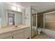 Well-lit bathroom featuring a vanity with a white countertop, mirrored closet doors, and a shower-tub combo at 4150 S Atlantic Ave # 104 B, New Smyrna Beach, FL 32169