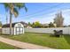 Spacious backyard with grass, palm tree, white vinyl fence and shed at 445 Virginia Ave, St Cloud, FL 34769