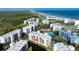 Stunning aerial view of beachfront condo complex with pool, tennis courts, and ocean views at 5300 S Atlantic Ave # 8-404, New Smyrna Beach, FL 32169