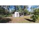 Small storage shed with attached covered porch, surrounded by mature trees and a grassy yard at 685 E French Ave, Orange City, FL 32763
