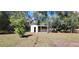 Well-maintained storage shed with a covered porch area, located in a serene and grassy backyard at 685 E French Ave, Orange City, FL 32763