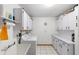 Bright laundry room features white cabinets, tile flooring, a utility sink, and a washer and dryer at 980 Buttercup Ter, Deltona, FL 32725