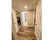 Hallway with wood-look tile, leading to a well-lit bedroom and bathroom with shower at 1000 Lake Of The Woods Blvd # 104F, Casselberry, FL 32730