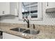 Modern kitchen sink featuring granite countertops and stylish black faucet, complemented by white hexagon tile backsplash at 1259 Vanderbilt Dr, Ormond Beach, FL 32174
