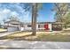 Charming single-story home featuring a bright red front door, carport, screened porch and well-maintained lawn at 129 S Marydell Ave, Deland, FL 32720