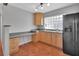 Sunlit kitchen features a black refrigerator, glass block window, and work space with cabinets at 129 S Marydell Ave, Deland, FL 32720