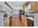 Galley kitchen with tiled floors features wood cabinets, granite countertops, and black appliances at 129 S Marydell Ave, Deland, FL 32720