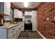 Galley kitchen featuring white cabinetry, stainless steel appliances, and brick accent wall at 1341 Imperial Dr, Daytona Beach, FL 32117